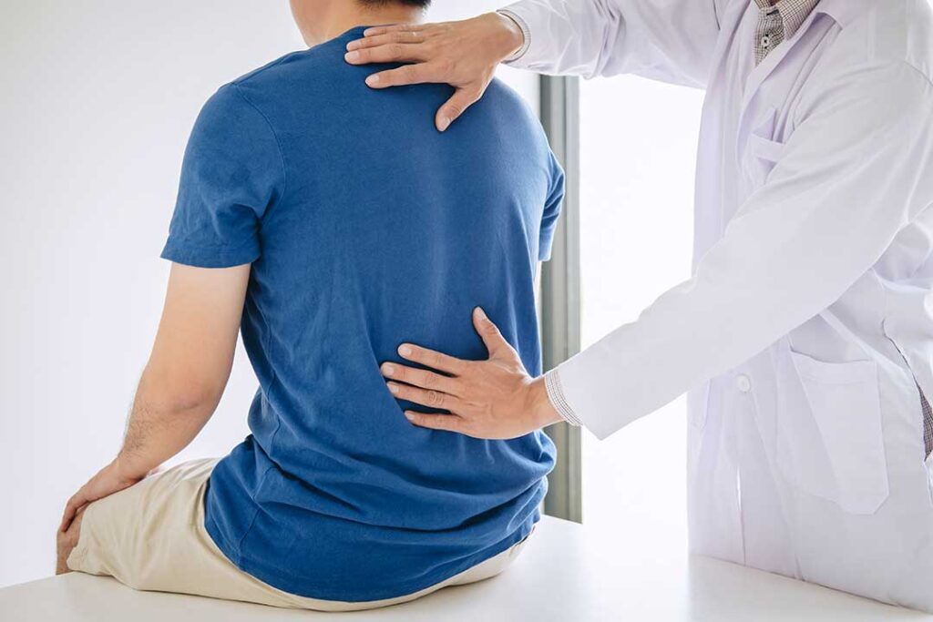 A patient in comfortable clothing talking with a healthcare professional in a medical office setting.