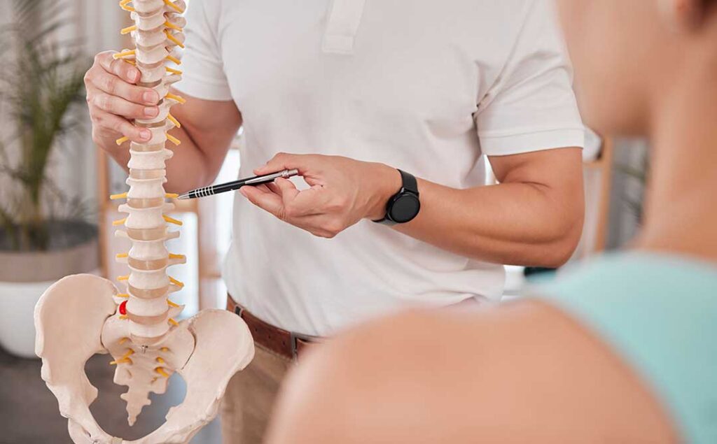 Person performing gentle spine mobility exercises in a bright home setting beside a chair.