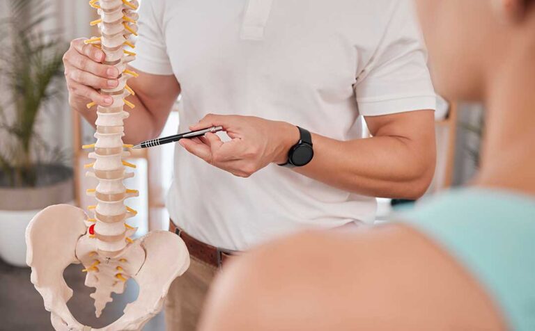 Person performing gentle spine mobility exercises in a bright home setting beside a chair.